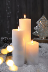 Burning candles and Christmas decor on artificial snow