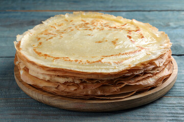 Stack of delicious crepes on blue wooden table, closeup