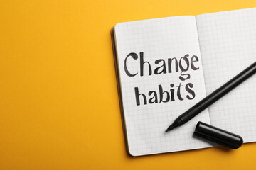 Open notebook with phrase Change Habits on orange background, top view. Space for text