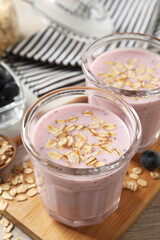 Glasses of tasty blueberry smoothie with oatmeal on table