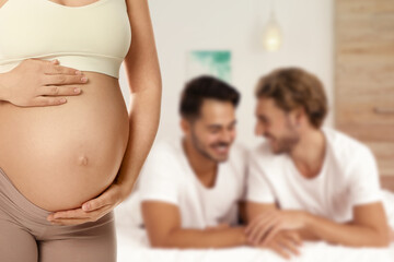 Surrogacy concept. Young pregnant woman and blurred view of happy gay couple indoors - obrazy, fototapety, plakaty