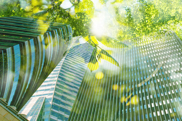 Go green concept. Low angle view of modern building and trees on sunny day