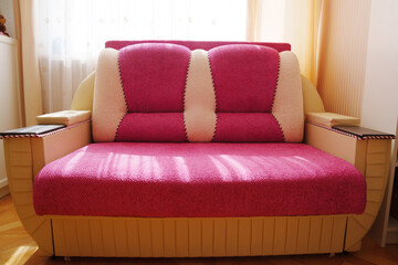 sofa bed made of pink fabric with wooden armrests. 