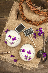 Vegan panna cotta dessert with fresh violet flower. Striped very peri color food, rustic style