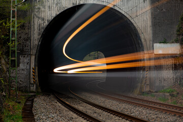 Fast train coming to light out of a tunnel with old concrete portal near Altena Germany in rural...