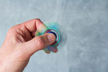 Man hand holding rotating metalic fidget spinner on marble background. Anti stress toy