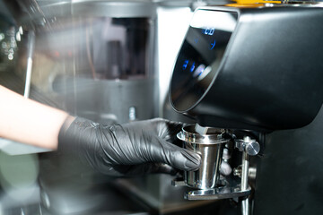 Close-up image of the coffee grinder machines in a coffee shop. Barista grinding freshly roasted coffee beans from a professional modern electric grinder into a powder. Cafe brewing Service Concept