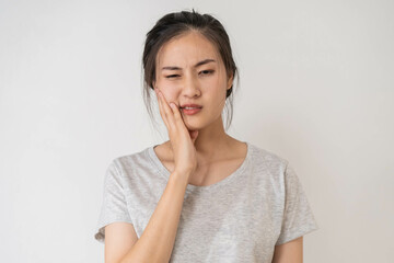 Closing eyes asian young woman touching cheek, face expression from toothache, tooth decay or sensitivity, Having tooth or teeth problem or inflammation, suffering from health. Sensitive teeth people