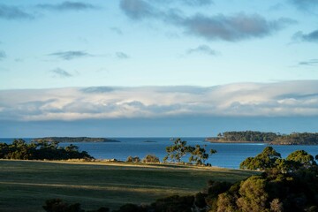 Farm looking out over the ocean, an organic grass farm and ranch, by the coast, beach and ocean. in Tasmania, Australia.