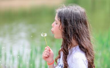 girl blowing dandelion in the garden