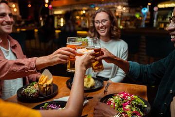 Diverse group of friends out for dinner making a toast with cocktails