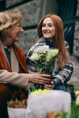 Granddaughter buying flowers for her grandmother on a street.