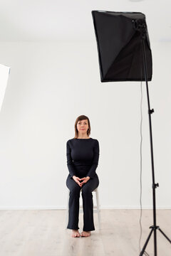 Woman sits on a chair, on her directional softbox