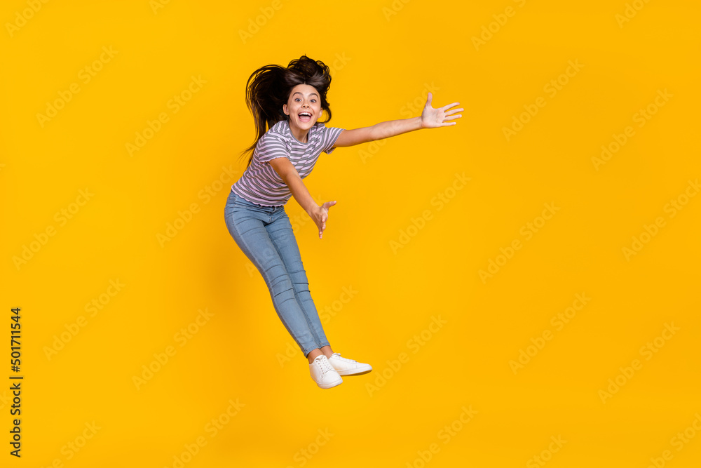 Poster Full body photo of young excited girl jump up hands blow cyclone isolated over yellow color background