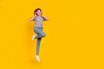 Fototapeta na wymiar Full length photo of young cheerful lady listen radio earphones jump mp3 melody isolated over yellow color background