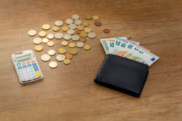 Banknoty euro i monety na stole z kalkulatorem i portfelem. Koncepcja finansów i budżetu. - obrazy, fototapety, plakaty