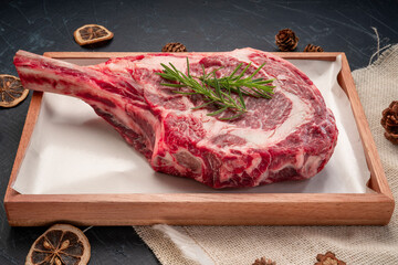 Fresh Tomahawk beef steak with rosemary on wooden plate, Tomahawk beef steak on black wooden...