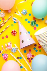Colorful carnival or party frame of balloons, streamers and confetti on yellow background. Vertical photo.