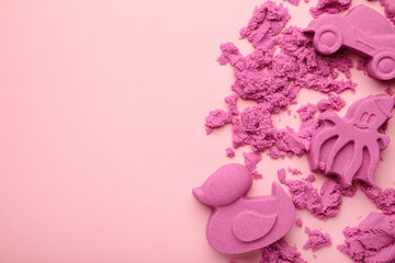 Pink kinetic sand for children, development and play at home with multi-colored sandbox molds on pink background.