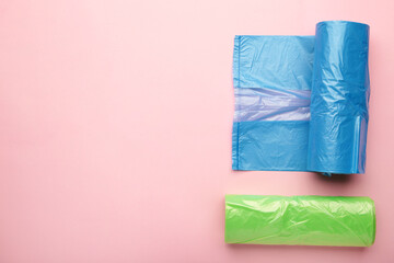 A lot of colored plastic bags rolls on a pink background.