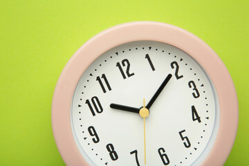Pink clock on green background. Top view.