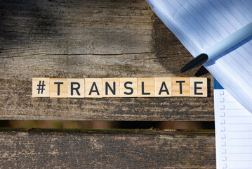 Wooden toy blocks with the text translate with pen and paper in the background