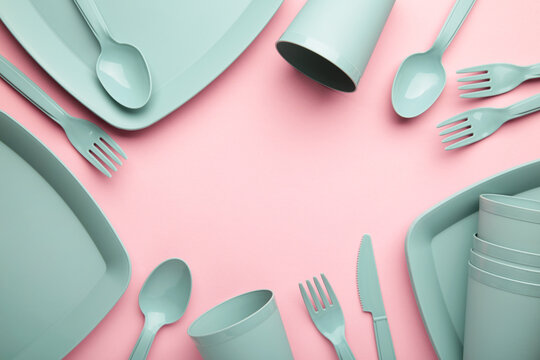 Bright plastic disposable tableware on pink background.