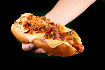 female hand showing american hot dog with bacon and crispy onion and melted cheese