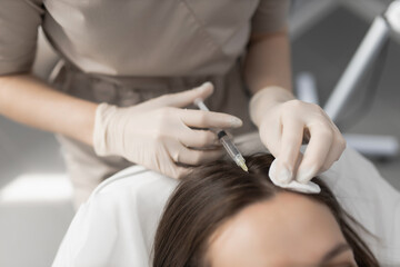 doctor cosmetologist makes mesotherapy injections for hair to a client. Hair restoration and care