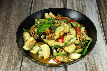 Traditional fried and stirred spicy fresh Thai eggplant mixed with mussel meat serving on the plate. 