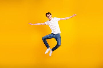Full body photo of young cheerful man good mood arms wings fly air jumper isolated over yellow color background