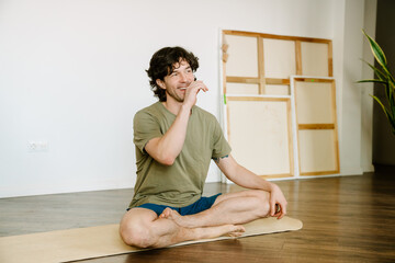 White man laughing and sitting on mat during yoga practice