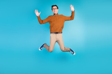 Fototapeta premium Full length photo of young man jump up wave hands hello energetic travel isolated over blue color background