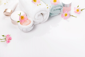 Obraz na płótnie Canvas Beauty and spa concept. Towel and skin care cosmetics with rose hips on a white background. Flat lay.