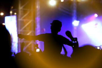 Viewers under the stage. The man with raised hands during summer festival rock concert.