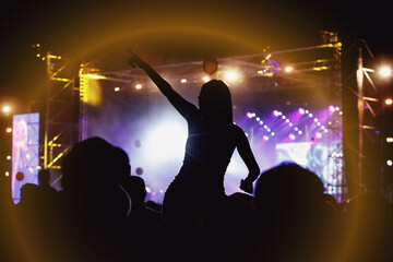 Fototapeta na wymiar Girl on shoulders in the crowd at a music festival