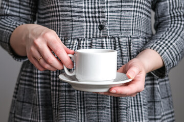 Coffee white cup and saucer in female hands. Mockup for design, branding, business.