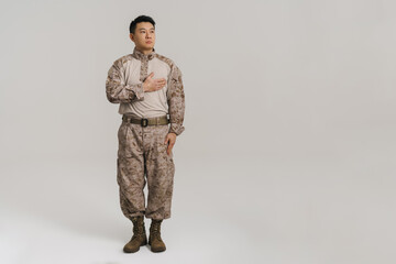 Asian military man wearing uniform holding hand on his chest