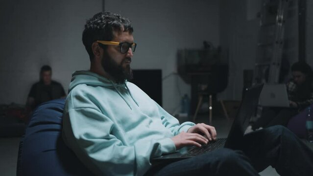 Close view of programmers typing on a laptop keyboard and working in a bomb shelter hearing missile strikes and explosions during the war