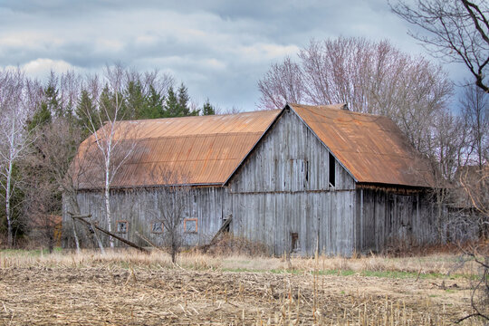 An old wooden barn sits idle on a country road in Ontario, Canada