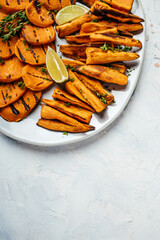Fried sweet potatoes with rosemary, paprika and chili peppers on white plate. Food recipe background. Close up vertical image. top view