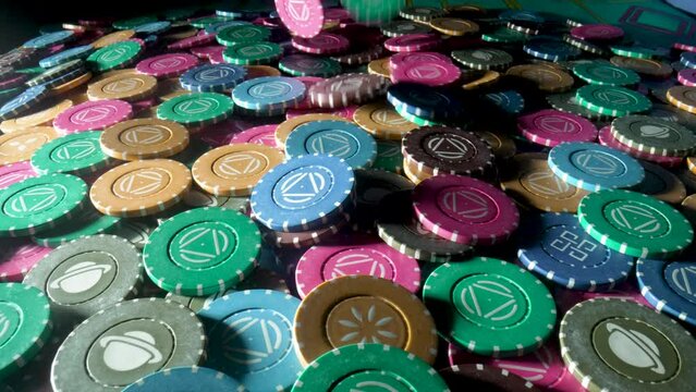 Casino chips on the gaming table in the casino. Chips falling on a pile close up in slow motion. The concept of gambling and entertainment. Win, poker betting, roulette, blackjack.