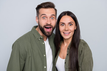 Portrait of attractive cheerful amazed couple spouses hugging news reaction isolated over grey pastel color background