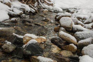 Fototapeta na wymiar A stream in the snow in winter.