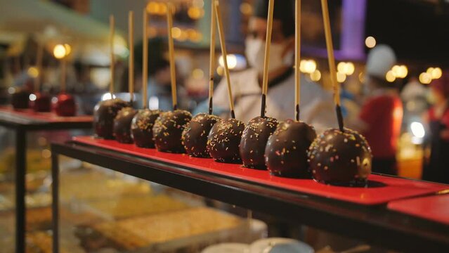 Rows of apples in sugar and chocolate syrup on a stick on a holiday. A treat for the guests.