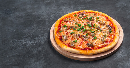 Pizza with mushrooms, tomatoes, cheese and herbs on a cutting board.