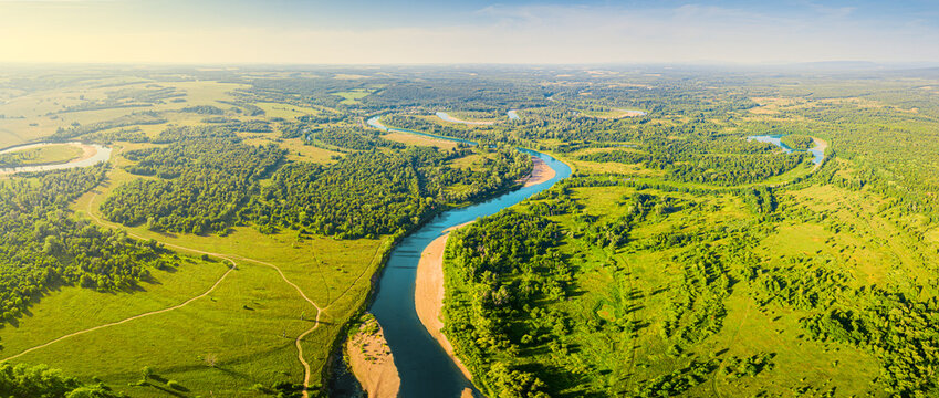 Aerial top view of a peaceful river valley among green plain. Summer scene and eco environment.