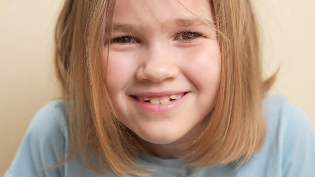 portrait of a cheerful little girl with blonde hair in a blue T-shirt. happy childhood. Emotions.