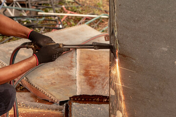 A factory worker cuts metal using an acetylene torch. Manual plasma cutting in a steel plant is...