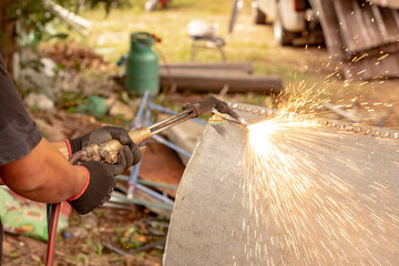 A factory worker cuts metal using an acetylene torch. Manual plasma cutting in a steel plant is full of sparks. gas fire blowing hot iron